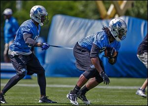 Detroit Lions running back Reggie Bush, left, holds back teammate Joique Bell during drills at training camp. Teammates admire Bush for the amount of extra work he puts in after practice.