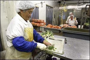 Juan Huang chops onions at Chariott Food. Sylvania schools are increasing their use of fresh fruits and vegetables, which is good for the bottom line of produce vendors such as Chariott in Toledo.