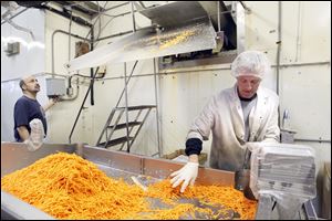 Warren Hawkins, right, bags carrots while Mike Okdie, owner of Chariott Foods, operates the shredder.