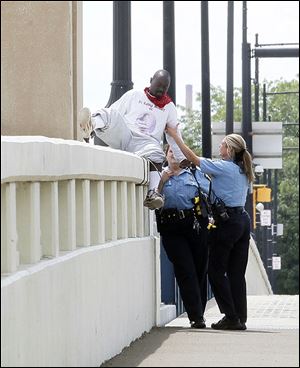 Toledo police officers help get George Armour III, 26, off the ledge of the Martin Luther King, Jr., Bridge after he threatened to jump. 