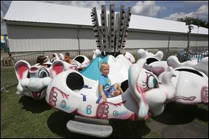 Caleb Singleton, 4, of Maumee sticks his tongue out while riding the Elephant Go Round at the Wood County Fair. Amusement rides for children, big and small, are a big fair attraction.