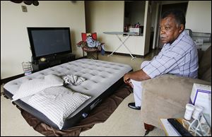 Jeffrey Fisher, president of the Alpha Towers residents’ association, sits in his apartment Tuesday. Mr. Fisher sleeps on an air mattress because of an infestation of bed bugs. The Fair Housing Center has filed a complaint against Alpha Towers for nonworking elevators, bed bugs, and other issues.
