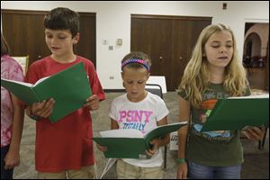 Joseph Buerk, 11, left, Chole Schalk, 10, center, and Lynley Acres, 12, right, sing together.