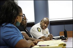 Police Chief Derrick Diggs speaks with One Village Council members Adita Miller, left, and Dawn Andrews at a meeting in North Toledo on Tuesday.