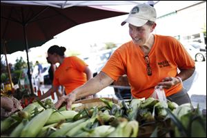 Cindy Bench of Bench Farms bags corn for a customer during the Farmer's Market in downtown Perrysburg. The market runs from 3 to 8 p.m. Thursdays.