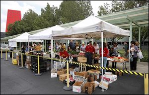 OC employees buy produce at the Toledo Farmers' Market, set up outside the company headquarters. Wednesday's event is to be repeated in the fall.
