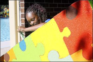 Earth Lyons, 14, of Toledo paints the mural at Roosevelt Pool.
