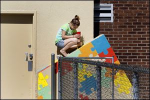 Ebony Hill, 18, of Toledo paints a cement block in an Arts Commission sponsored youth art project at Roosevelt Pool in Smith Park.