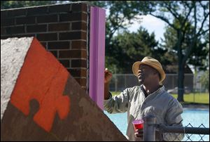Local artist Yusuf Lateef, a former Young Artists student, paints the mural at Roosevelt Pool.