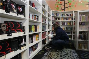 Caitlin McCallum, 24, a graduate student at the University of Toledo, looks over books in the children's section of Ukazoo. The new and used bookshop in Toledo, Ohio will close its retail operation on Aug. 16.