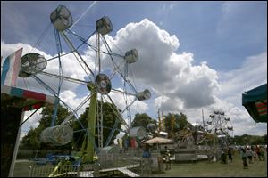 Rides spin as fair goers walk the grounds in the sunshine during this year's Wood County Fair Tuesday in Bowling Green.