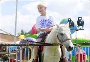 Logan Mocniak, 7, a second-grade student at Regina Coeli School, rides a pony during the school's annual festival on Saturday.