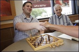 Tom Bush, of West Toledo, shakes hands with an opponent, who declined to be named, after a game of chess as he and Bill Brewer, 84, of Adams Township, right, talk at a Wendy's in Maumee.