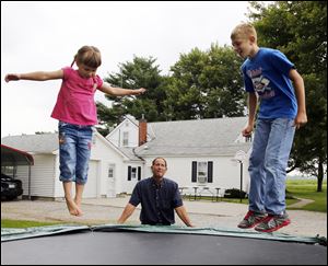 David Flowers watches his children Amy, 4, and Joshua, 11, play on a trampoline outside their home. Mr. Flowers is being recognized by the Ridge Project and Hope 4 Toledo as a role model. 