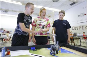 Austin Dazley, left, 13, ‘gives five' to Dianna Dohm, 16, a Bedford senior, as they and Nick Staley, 12, get their robot to perform a task during the Bedford robotics camp. Dianna was a student volunteer.