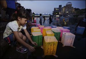 A girl releases a paper lantern for the repose of the soul of her great grandmother who died in the atomic bombing in the Motoyasu River with the backdrop of the Atomic Bomb Dome in Hiroshima, western Japan, Tuesday.