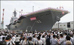 Japan's new warship Izumo, which has a flight deck that is nearly 820 feet long, is unveiled in Yokohama, south of Tokyo, today.