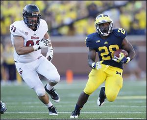 University of Michigan player Fitzgerald Toussaint, 28, races past University of Massachusetts player Kevin Byrne, 93, during the third quarter at Michigan Stadium in Ann Arbor, Sept. 15, 2012.