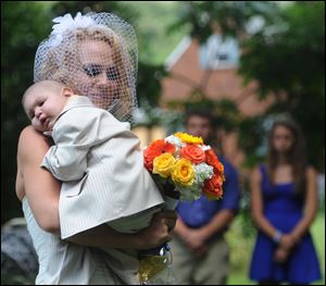 Christine Swidorsky carries her son and the couple's best man, Logan Stevenson, 2, down the aisle to her husband-to-be Sean Stevenson during the wedding ceremony in Jeannette, Pa., Saturday.