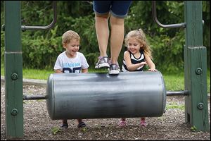 CTY SylvaniaRover07p Siblings Jackson, 2, and Sophia Wells, 3, of Sylvania, laugh as they push the rolling cylinder their aunt Abbie Wells, of Luna Pier, Mich., runs on while playing at Burnham Park on Tuesday, August 6, 2013, in Sylvania. As summer winds down, the park continues to be a popular spot for kids and their parents.   THE BLADE/KATIE RAUSCH