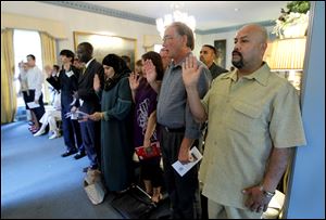 Joel Guzman-Martinez, right,  takes the Oath of Allegiance with others during a Naturalization Ceremony in the Manor House at Wildwood Preserve Metropark.