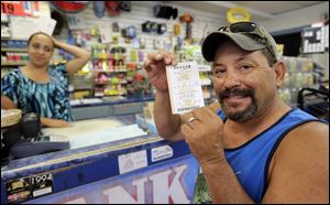 Tony Valdez, right, shows off his Powerball lottery ticket he purchased from Vanessa Sanchez, left, Wednesday in San Antonio.