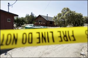 Police tape lines the perimeter of a partially burned home Tuesday near the U.S.-Mexico border in Boulevard, Calif. The husband of a woman whose body was found in the house said Tuesday that he knew the man suspected of killing his wife and abducting one or both of their children.