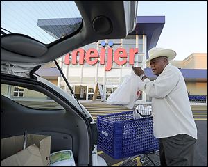 Lee Greenwood of Southfield, Mich., loads his car after shopping at the Meijer that recently opened in Detroit. The chain is boosting its staff in response to growth and the looming holiday season.