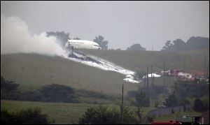 Debris burns as a UPS cargo plane lies on a hill at Birmingham-Shuttlesworth International Airport after crashing on approach today.