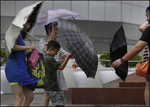 Tourists battle against strong wind near the waterfront in Hong Kong today as Typhoon Utor lashes Hong Kong with wind and rain.