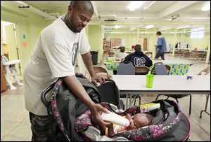 Randall Patterson feeds his daughter, Randi, 4 months, a bottle in her pram. He is among the graduates of Baby University.