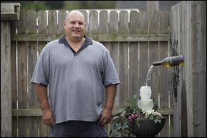 Toledo resident George Seambos stands next to his homemade wine bottle water fountain.