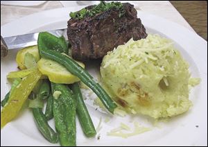 A grilled filet with Bernaise sauce served with mashed potatoes and mixed vegetables.