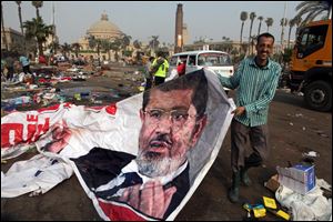 An Egyptian pulls a banner of Egypt's ousted President Mohammed Morsi near debris left at a protest camp in Nahda Square, Giza, Cairo, Egypt today.