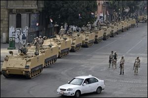 Egyptian army soldiers take their positions on top and next to their armored vehicles while guarding an entrance to Tahrir square, in Cairo, Egypt today.