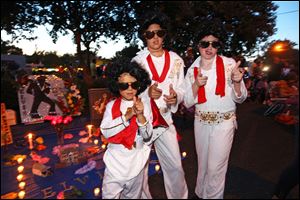 Nicholas Woodlief, 7, left, his sister Annabelle Woodlief, 11, and friend, Eli Crain, 11, right, strike an Elvis Presley pose at Graceland, Presley's home, before the annual candlelight vigil Thursday in Memphis, Tenn.