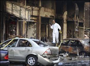 A Lebanese army investigator walks with a camera on a burned car as he inspects the site of a car bomb explosion in southern Beirut, Lebanon, today.