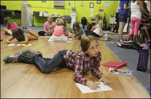 Aubrey Schaller, 9, of Perrysburg, works on an advertisement for a product at the Broadway-Bound Summer camp.