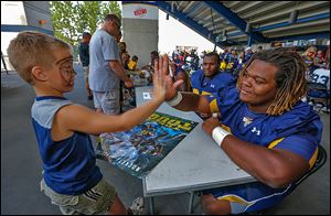 Kyler Koopmans, 5, of Toledo, high-fives UT defensive lineman Marquise Moore after getting an autograph during Fan Appreciation Day at the Glass Bowl.