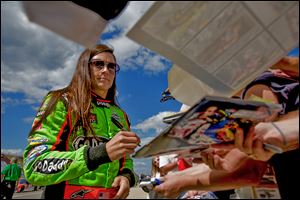 Danica Patrick signs autographs for fans before taking her qualifying lap for the NASCAR Sprint Cup Series at Michigan International Speedway. She will start 28th in today’s Pure Michigan 400.