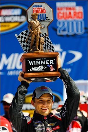 Driver James Buescher holds up the Michigan National Guard 200 trophy after winning Saturday at MIS.