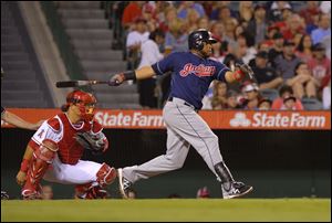 Cleveland Indians' Carlos Santana, right, hits an RBI single as Los Angeles Angels catcher Hank Conger looks on during the fourth inning.