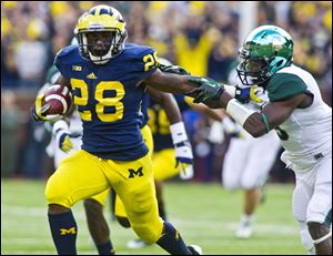 Michigan running back Fitzgerald Toussaint (28) holds back Michigan State safety Isaiah Lewis (9) during the second quarter of an NCAA college football game.