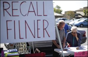 Greg Timms, left, signs a petition to recall San Diego Mayor Bob Filner, alongside Tana Piontek, right, at a stand set up in the parking lot of a shopping center Wednesday in San Diego.