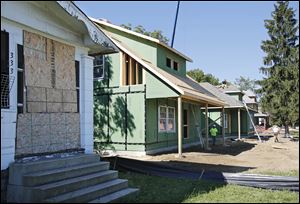 Two new homes, part of the Legacy Homes project, are under construction next to a vacant house in the 300 block of West Delaware Avenue in Toledo.