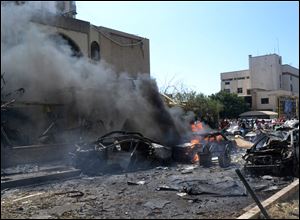 Burned and destroyed cars are seen at the entrance of a mosque, left, which was attacked by a car bomb, in the northern city of Tripoli, Lebanon today.