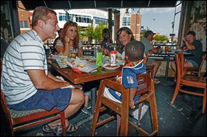 Dave Mierzwiak, left, daughter Andria, wife Kathleen, and Achiga D'or, 2, eat at Ye Olde Cock n' Bull before a Mud Hens game.
