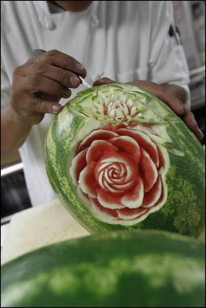 Food artist Tien Pham carves a flower into a watermelon while working in the Sylvania Country Club kitchen.