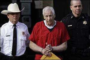 Former Penn State University assistant football coach Jerry Sandusky, center, is taken from the Centre County Courthouse in October, 2012.