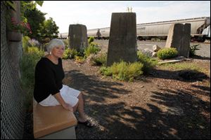 Bev Newell watches a passing train on Oakdale at White streets in Toledo. She planted a garden there and loves to watch the trains go by. She is sitting on a bench she made for the garden.